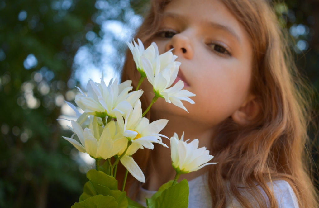 Little girl smelling white flowers